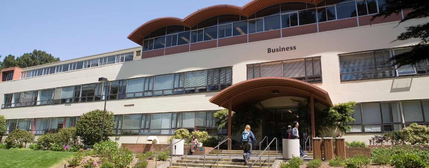 Marketing student walks up the steps to the Business building
